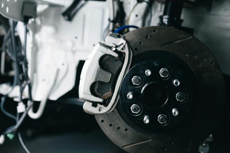 Detailed view of a car's brake caliper and disc in a workshop setting.